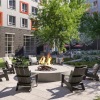 Outdoor lounge at our apartments for rent in Everett, MA, featuring chairs around a fire pit with a lawn and trees.