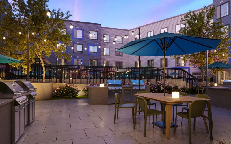 Outdoor lounge at our apartments for rent in Everett, MA, featuring outdoor furniture with umbrellas and grill stations.
